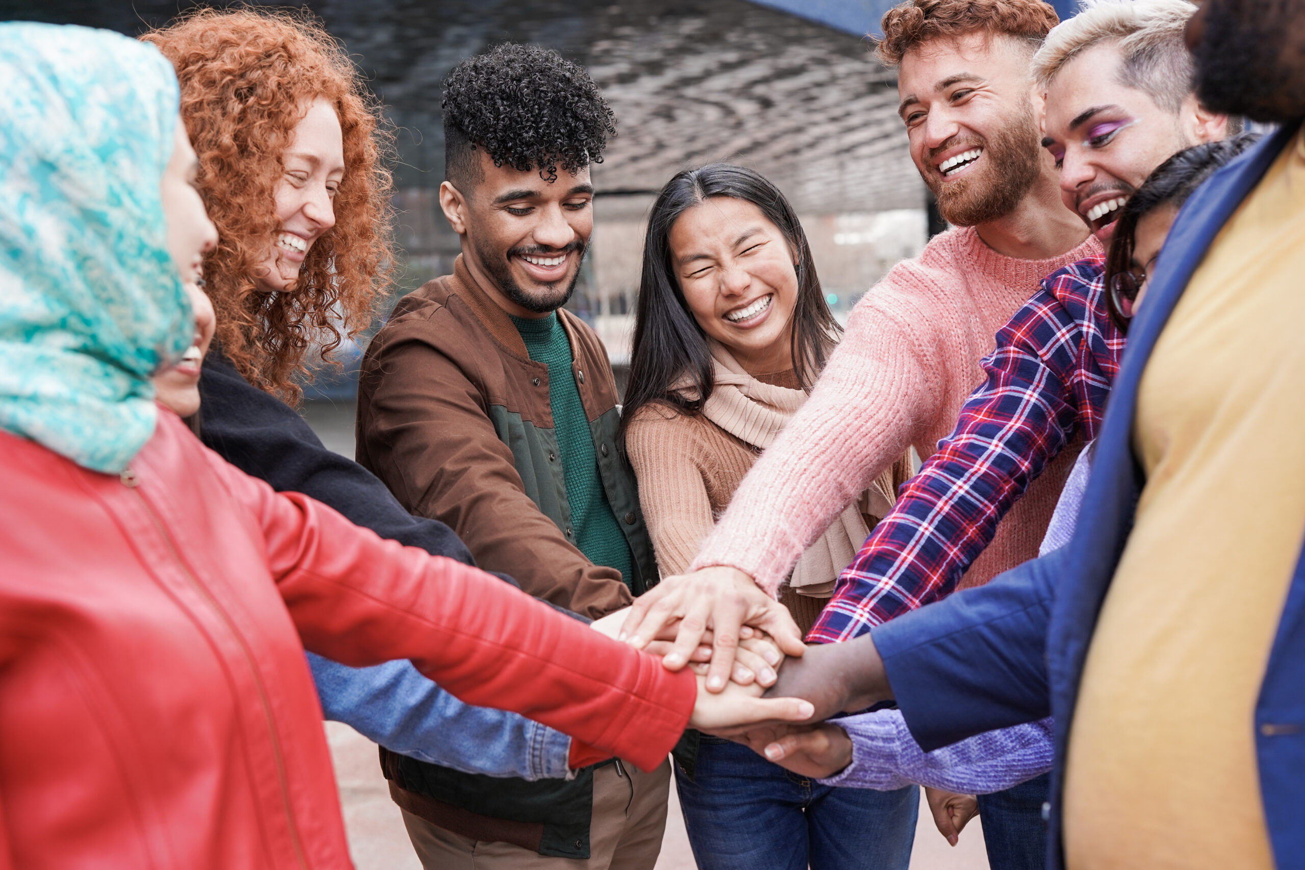 Group of young multiracial people stacking hands outdoor